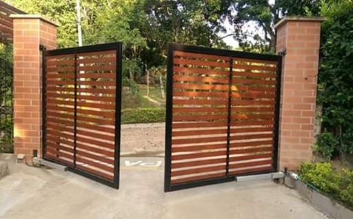 automatización, portón batiente de madera y metal con motores abajo.